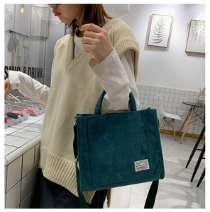 Close-up of deep green corduroy tote bag featuring visible texture and white brand label