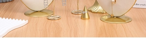 Modern jewelry display stand set with gold metal and beige velvet on a wood surface
