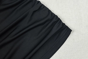 Detail shot of the black ruched fabric texture and delicate side stitching on the mini dress