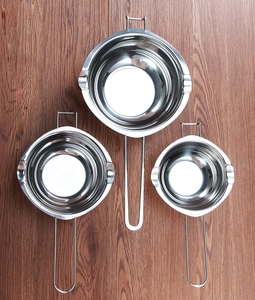 Detailed overhead view of three stainless steel melting pots in different sizes on wood