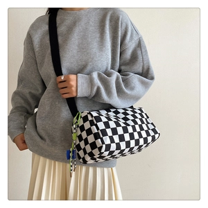 Detail of checkered canvas bag featuring SORAKA blue label and decorative cords