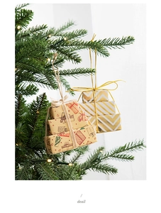 Mini Christmas gift box ornaments hanging on a festive tree with warm lights detail