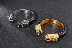 Detailed view of silver and gold dragon-head bracelets with black leather texture