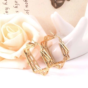 Detailed shot of gold geometric square earrings styled with elegant white roses