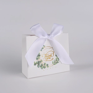 Close-up of white paper gift bag with eucalyptus wreath design and white silk bow detail