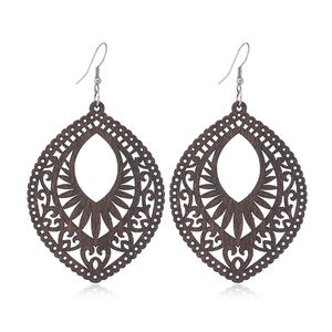 Macro view of dark brown teardrop wood earrings with intricate bohemian hollow patterns