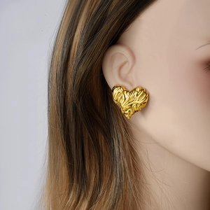 Golden 304 stainless steel heart earrings with irregular texture shown on a model