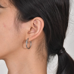 Silver knot earring close-up on model showing the minimalist stainless steel design