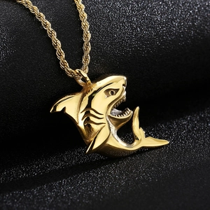 Macro view of gold shark pendant with rope chain on a textured black surface