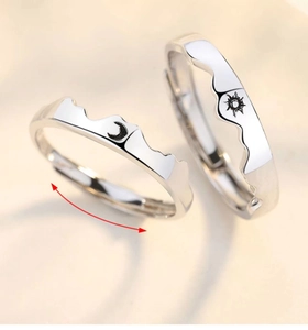 Detail of adjustable sun and moon couples rings in polished silver with engraved symbols
