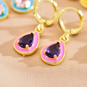 Detailed macro view of purple teardrop gemstone earrings with pink enamel and gold plating
