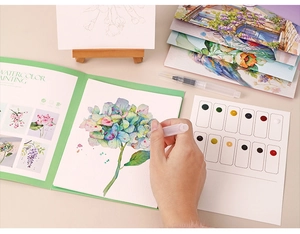 Close-up of DIY watercolor painting set showing a hydrangea sketch being colored