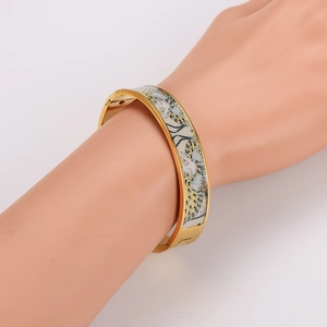 Luxury gold stainless steel bangle with colorful enamel patterns worn on a model's wrist