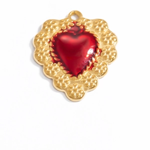 Detailed view of red heart pendant with ornate gold embossed floral metal border