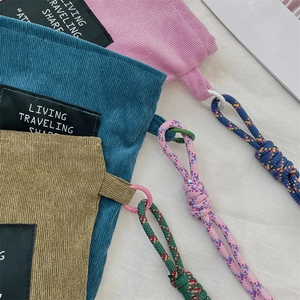 Detail of corduroy phone bags in pink, teal and khaki with woven rope decorations