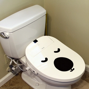Funny cartoon expression sticker on a white smart toilet seat lid for bathroom decor