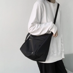 Practical casual black canvas messenger bag on person showing large capacity and fit