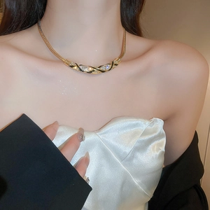 Close-up of gold snake chain necklace with black enamel inlay and sparkling crystal stones