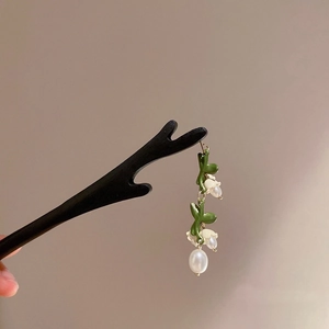 Détail d'un pic à cheveux en bois vintage avec gland de muguet et feuille verte
