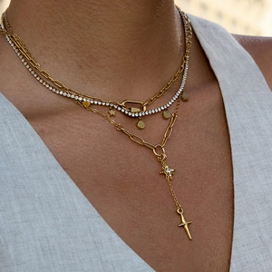 Gros plan de colliers multicouches dorés avec pendentifs étoile et croix en acier inoxydable