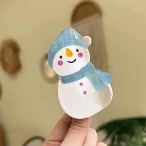Gros plan d'une pince à cheveux bonhomme de neige avec bonnet et écharpe en acétate poli
