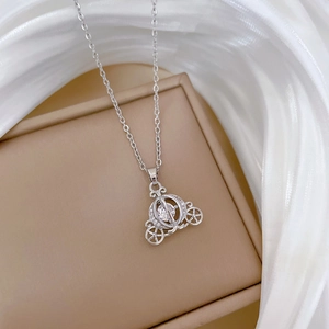 Macro shot of a silver carriage pendant with a crystal stone on beige jewelry box