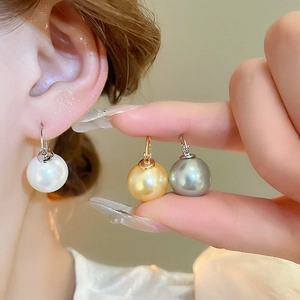 Vue détaillée de boucles d'oreilles perles géométriques aux tons blancs et dorés