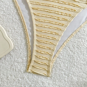 Detail of pale yellow bikini bottom featuring ruched fabric and scalloped edges