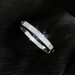 Macro shot of silver titanium steel bracelet featuring engraved Roman numerals on silk