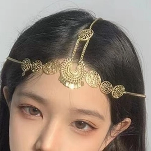 Detail of golden bohemian forehead chain with crescent pendants on model's head