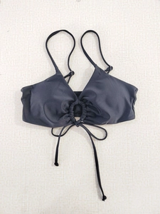 Detailed flat lay of black bikini top with halter neck straps and center ring detail
