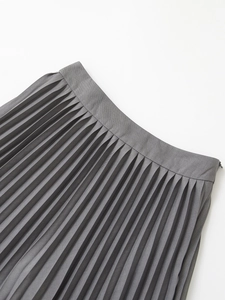 Detail of high-waisted pleated skirt showing fine accordion pleats and fabric texture
