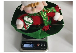 Detailed close-up showing a 163g Christmas elf ornament on a scale for weight check