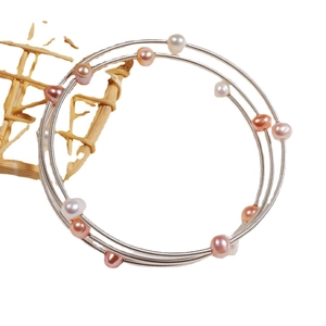 Three-layer silver spiral wire bracelet with multi-colored freshwater pearls on white background