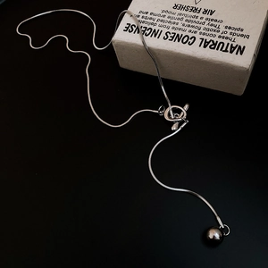 Close-up of silver snake chain necklace with round bead and OT toggle clasp closure