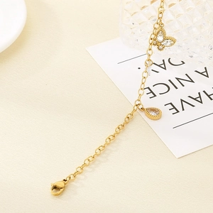Close-up of golden stainless steel anklet with butterfly and water drop crystal pendants