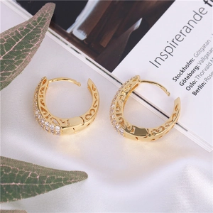 Macro shot of gold-plated hoop earrings with pave-set zircons and hollow wave patterns