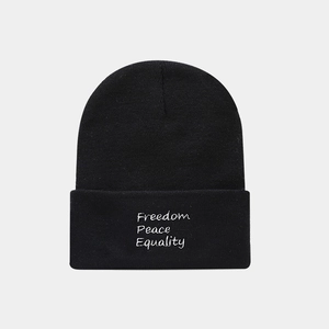 Close-up of black knit beanie featuring white embroidered Freedom Peace Equality text