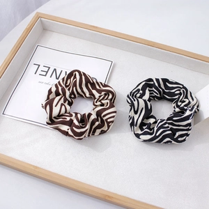 Détail de chouchous à motif zébré marron et noir sur un plateau de présentation en bois