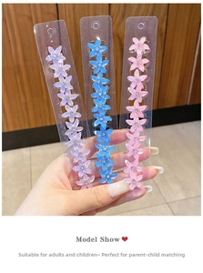 Détail de trois pinces à cheveux florales en violet, bleu et rose avec des strass fins