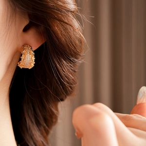 Gros plan de boucles d'oreilles dorées en forme de C avec oxydes de zirconium sur un mannequin