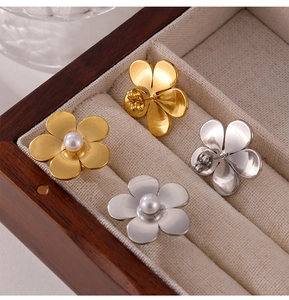 Gros plan de boucles d'oreilles fleurs en acier titane avec perles dans un coffret