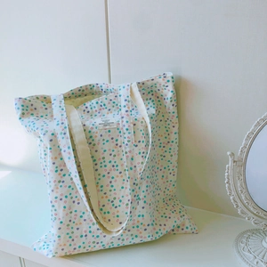 Detail einer floralen Canvas-Tasche mit bunten Punkten und weißem Etikett-Design