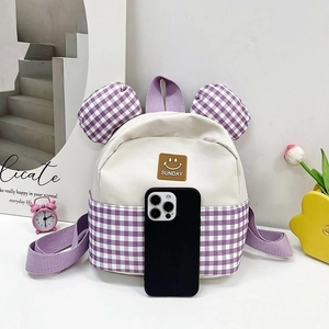 Detail of small purple plaid kids backpack with cute ears next to a phone for scale
