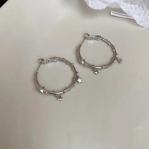 Macro detail of silver star hoop earrings with punk spikes on a minimalist white surface