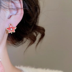 Close-up of red maple leaf earring on model showing elegant fit and golden edges