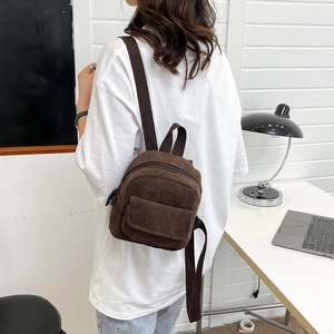 Model wearing dark brown corduroy mini backpack showing casual style and size scale