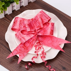 Detail view of a large red wedding bow with embossed rose patterns on a white decorative plate