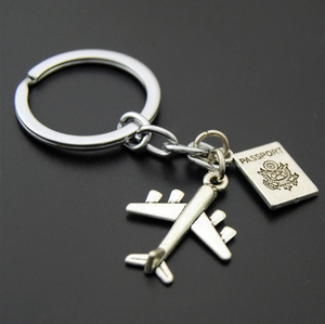 Macro shot of antique silver airplane and passport pendants on a steel keyring