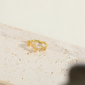 Minimalist gold vine ring with pink marquise stones on textured marble background